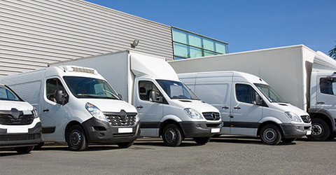 a row of white delivery vans parked outside a modern building showcasing a variety of sizes for transport vehicles perfect for logistics and delivery services with twelve options available