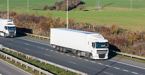 two large trucks traveling on a highway with green fields in the background showcasing modern transport and logistics solutions five times more efficient